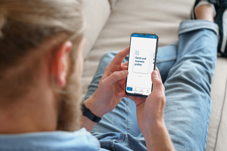 Man lying on sofa and using AusweisApp on his smartphone